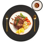 Steak with vegetables on a white plate with gold cutlery on a black woven placemat.