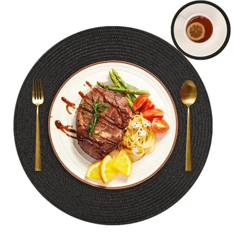 Steak with vegetables on a white plate with gold cutlery on a black woven placemat.