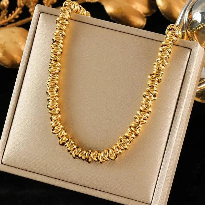 Gold necklace on a beige jewelry box with blurred gold objects in the background