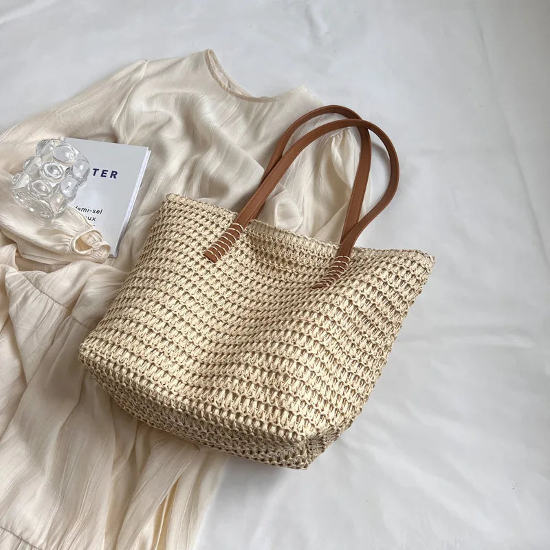 Woven straw bag with brown handles on a light fabric background