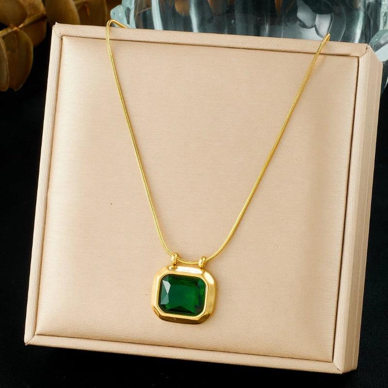 Gold necklace with a green pendant on a beige card