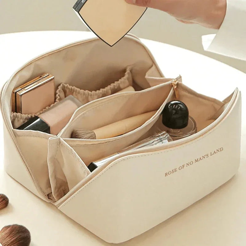 Beige cosmetic bag with compartments containing makeup items, held by a hand.