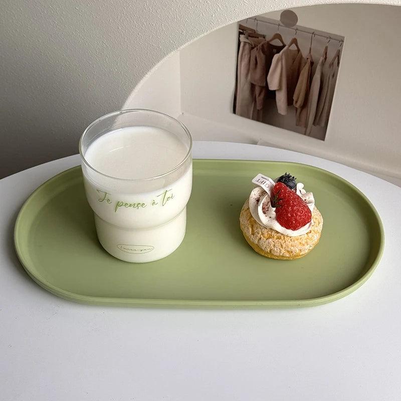 Glass of milk and dessert on a green tray with a mirror in the background