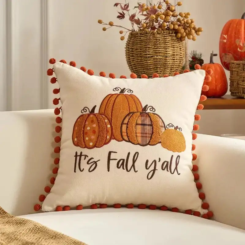 Decorative pillow with pumpkins and 'It's Fall y'all' text on a couch.