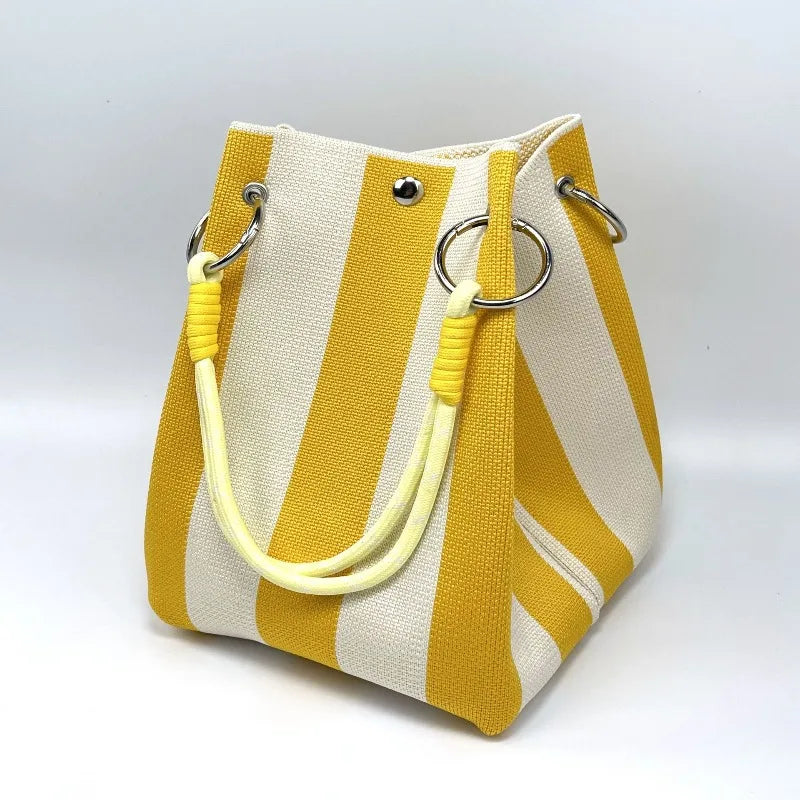 Yellow and white striped handbag with yellow handles on a light gray background