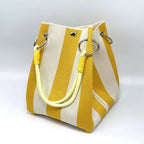 Yellow and white striped handbag with yellow handles on a light gray background