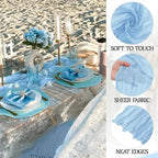 Table setting with blue tablecloth and decor on a beach, showing fabric texture details.