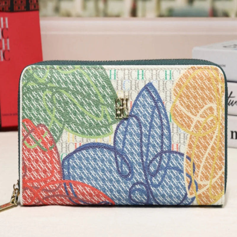 A zip-around wallet with a colorful abstract floral pattern on a textured woven background, displayed on a light surface with a blurred city street in the background.