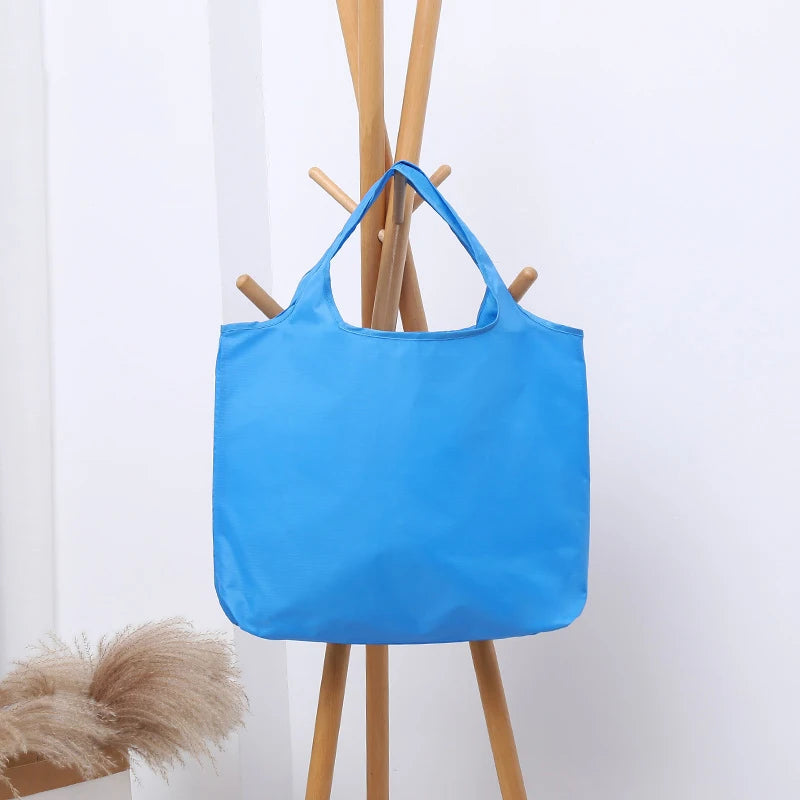 Blue tote bag hanging on a wooden coat rack against a white background