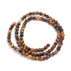A coiled strand of round tiger's eye beads in shades of brown, tan, and black, displayed on a clean white background.