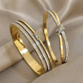Two gold bangles with diamond accents on a beige fabric background
