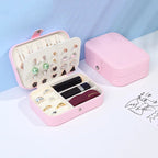Pink jewelry box with compartments for earrings, rings, and lipsticks on a light blue background.
