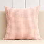 Pink textured pillow on a beige couch with a light gray wall background