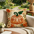 A square decorative throw pillow with a large orange pumpkin design and floral border, resting on a beige outdoor sofa in a garden setting.