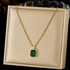 Gold necklace with a green pendant on a beige display box.