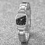 Silver watch with a black face on a gray glittery background