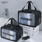Black washbag with transparent window on a bathroom counter with books and toiletries.