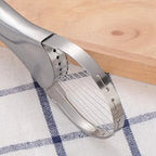 Metallic kitchen tool on a checkered cloth with wooden surface