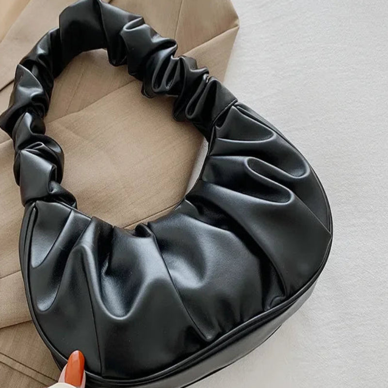 Black satin hair bun holder on a neutral background