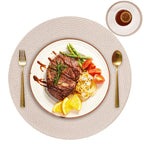 Steak with vegetables on a white plate with gold cutlery on a textured beige placemat.