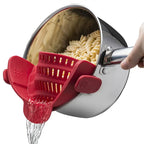 Red kitchen tool being used to drain pasta from a pot