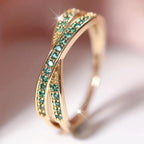Gold ring with green gemstones on a soft focus background