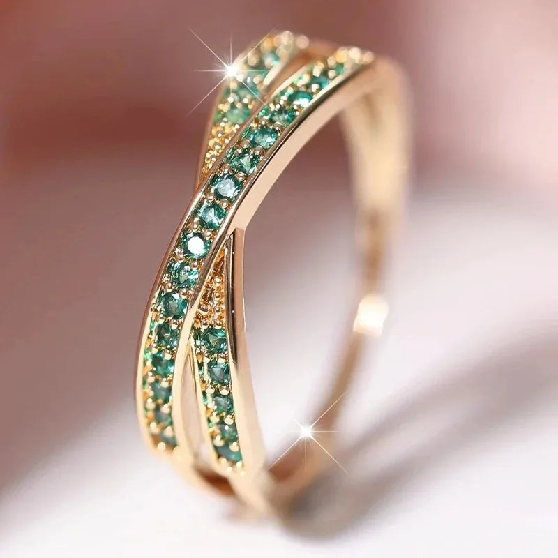 Gold ring with green gemstones on a soft focus background