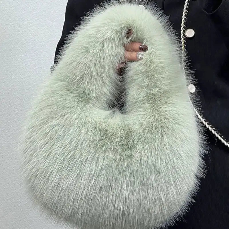 Light green fluffy handbag held by a person wearing a dark coat.