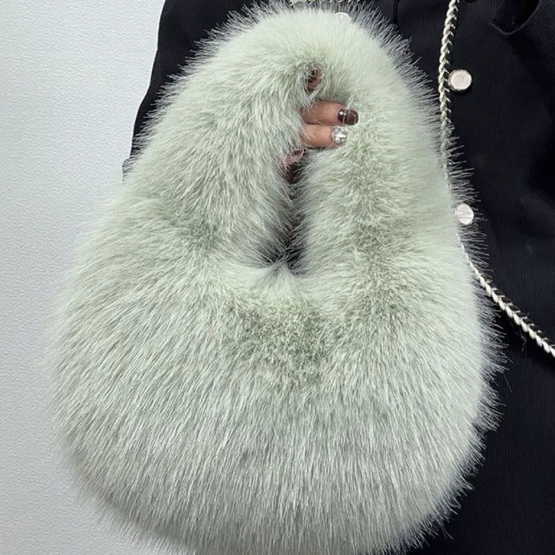 Light green fluffy handbag held by a person wearing a dark coat.