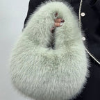 Light green fluffy handbag held by a person wearing a dark coat.