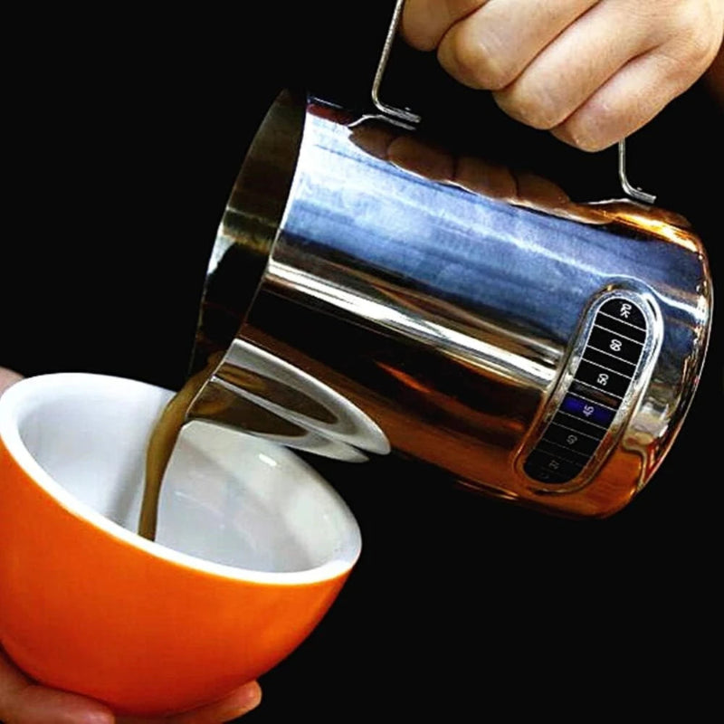 Metallic milk frother being used to froth milk in an orange mug.