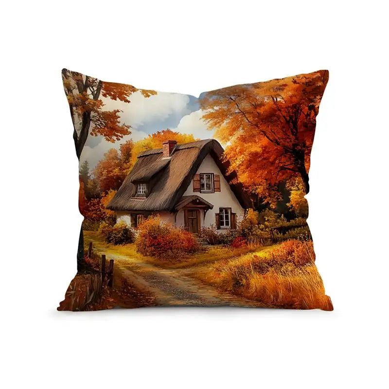 A square throw pillow featuring a printed autumn landscape scene with a thatched cottage, orange trees, a dirt path, and a cloudy sky, shown on a plain white background.