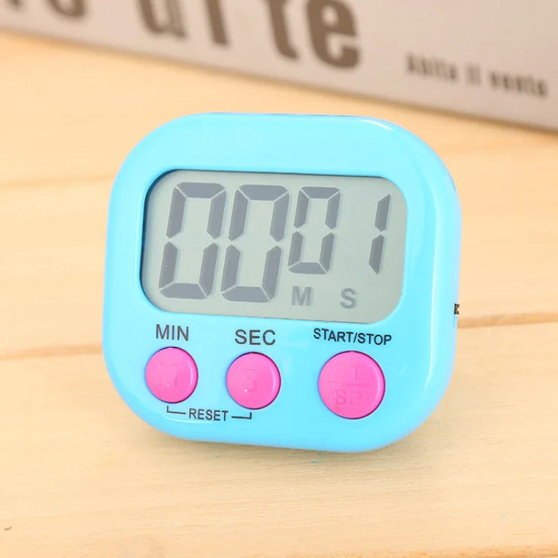 A light blue digital kitchen timer with three pink buttons and a gray LCD display showing 00:01, placed on a light wooden surface.