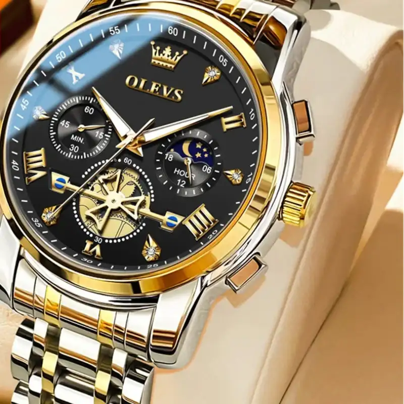 Gold and silver watch with black face on a beige background, featuring the OLEVS brand.