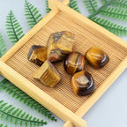 Tiger's eye stones on a wooden tray with fern leaves in the background