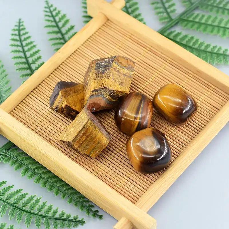 Tiger's eye stones on a wooden tray with fern leaves in the background