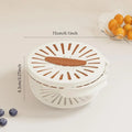 White kitchen tool with brown accents on a light beige background, showing measurements and a small bowl of oranges.