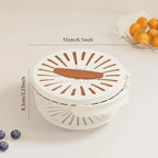 White kitchen tool with brown accents on a light beige background, showing measurements and a small bowl of oranges.