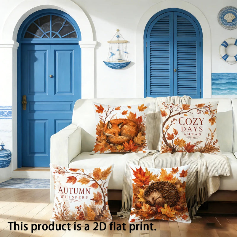 Three decorative throw pillows with autumn-themed 2D flat prints are arranged on a white sofa in a nautical-style room with blue doors and walls. The pillows feature designs including a fox in autumn leaves, a hedgehog, and the text 'COZY DAYS AHEAD' and 'AUTUMN WHISPER'.