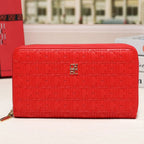 A red CHANEL zip-around wallet with an embossed monogram pattern and a gold CC logo, displayed on a white surface with a blurred background.