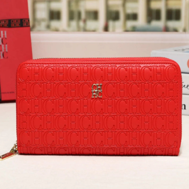 A red CHANEL zip-around wallet with an embossed monogram pattern and a gold CC logo, displayed on a white surface with a blurred background.