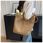 Person holding a woven bag with flowers against a neutral background