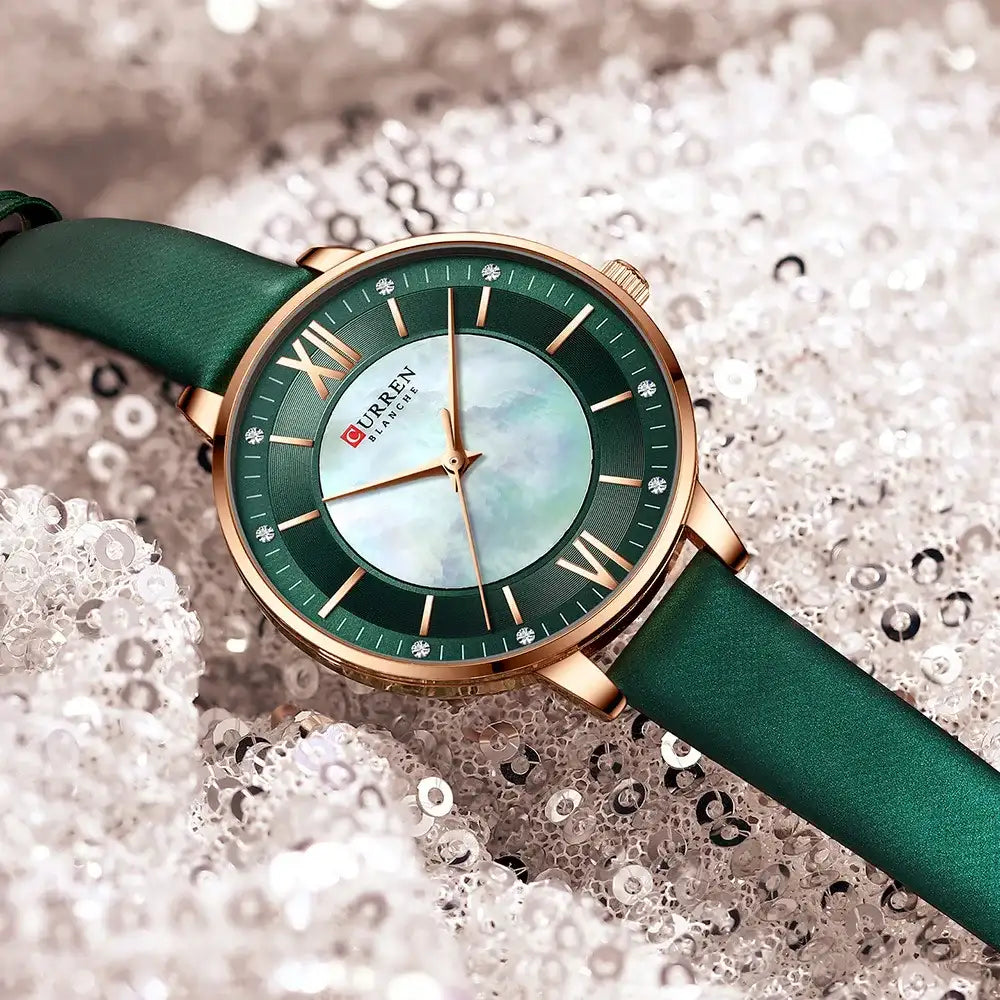 Green watch with gold accents on a textured white background
