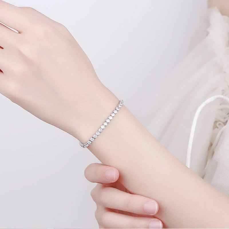 Silver bracelet on a person's wrist against a plain background