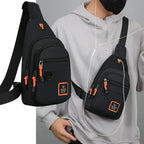 Person wearing a black crossbody bag with orange accents, holding earphones.