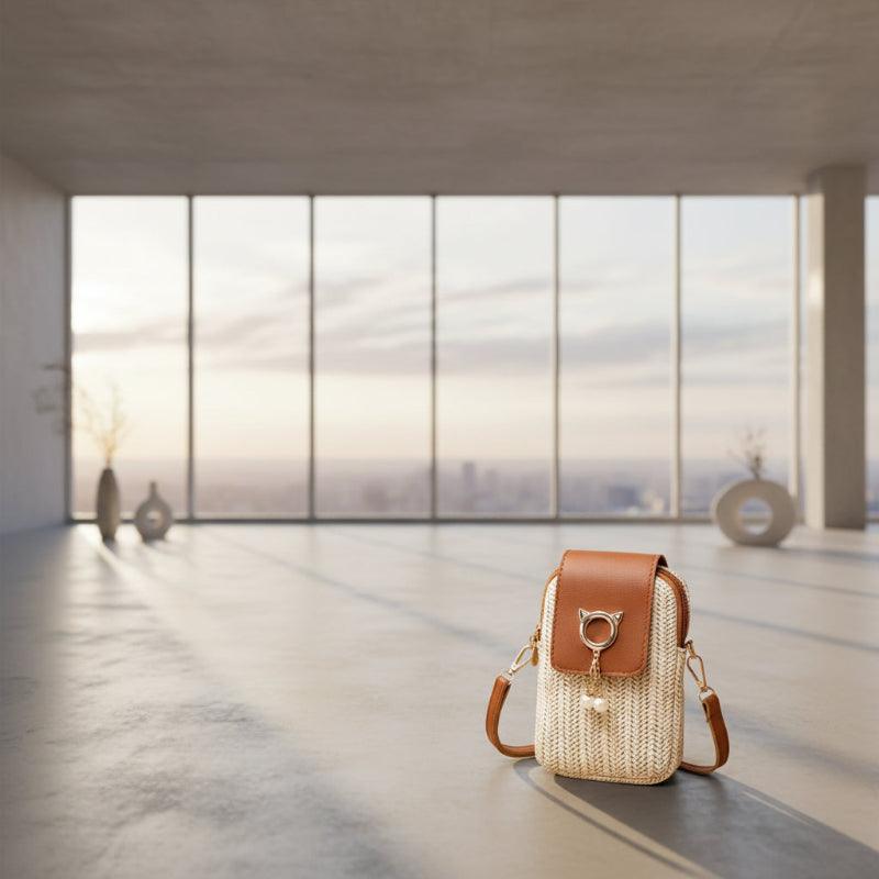 Woven handbag with brown leather accents and a cat-shaped charm on a wooden surface.