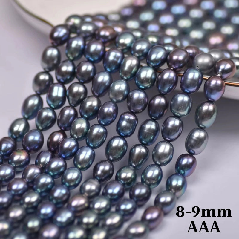Close-up of strands of iridescent oval pearl beads in a dark blue-gray color with purple and green shifts, with text reading '8-9mm AAA' in the bottom right corner.