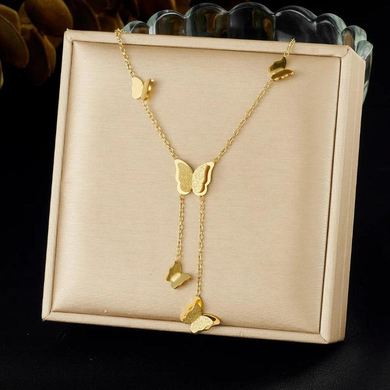 Gold butterfly necklace on a beige display card with a black background