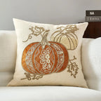 Decorative pillow with embroidered pumpkins on a beige couch.