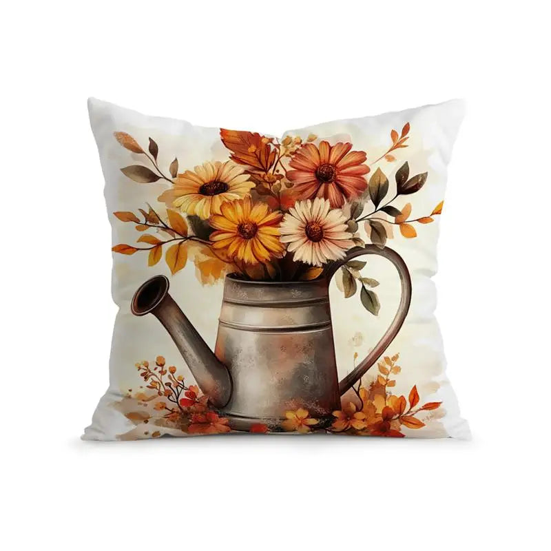 A square decorative throw pillow featuring a printed design of a rustic metal watering can filled with orange, yellow, and white flowers, set against a plain white background.